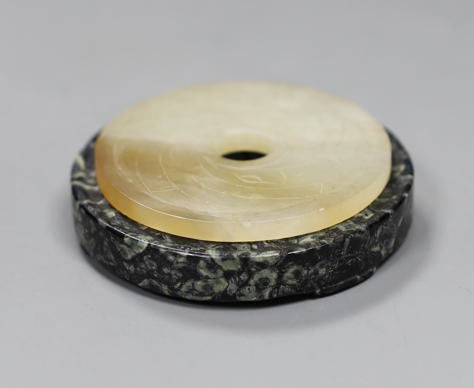 Two Chinese bi discs; in bowenite jade and black and green hardstone, largest 7cm diameter